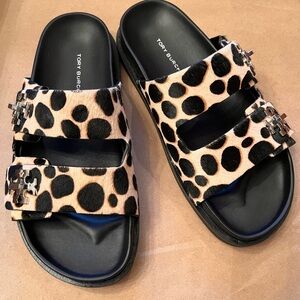 Tory Burch Turnlock Sport leopard print calf hair slides with silver tone logo.